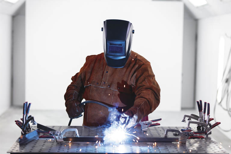 A student welding with a faceshield