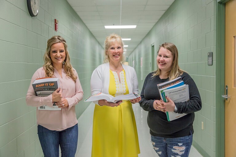 three women smiling in a hallway