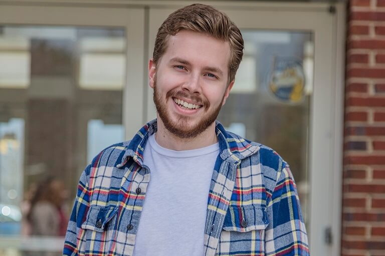 man in flannel shirt smiling at the camera
