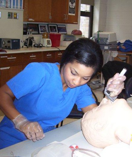 A female respiratory care student placing a breathing device in a practice manikin.