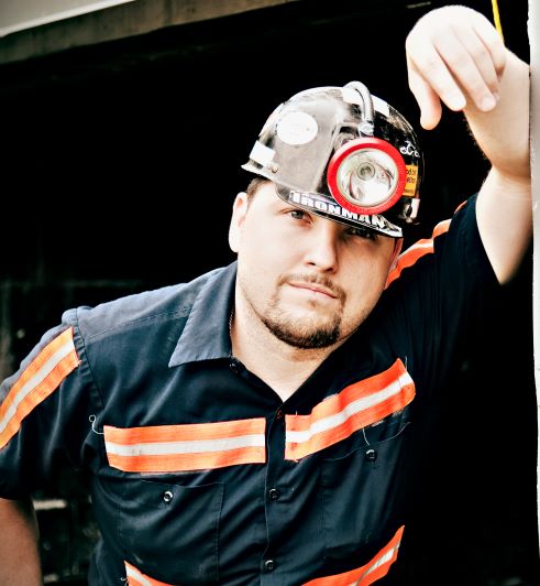 A coal miner wearing a helmet and reflector uniform.