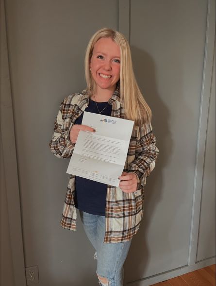 Ally Wilder poses for a photograph while she is holding her scholarship award letter.