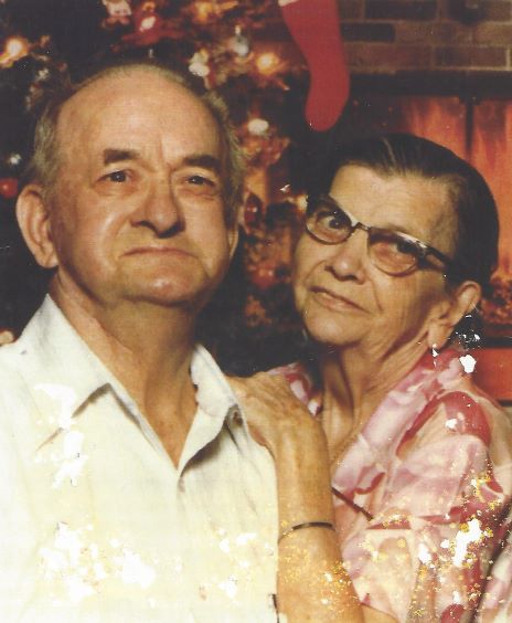 Barney and Mary Sword pose for a portrait. The background is a Christmas scene.