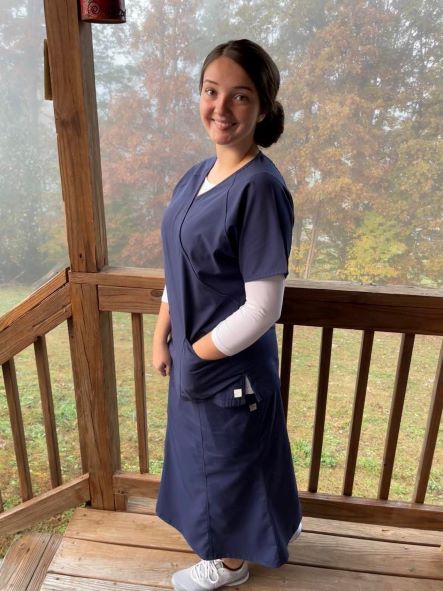 Clara Warren stands on her porch with a wooded scene behind her.