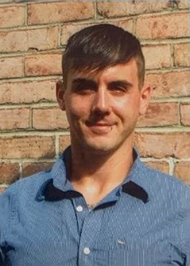 A headshot of Frank Robinette. A brick wall is behind him.