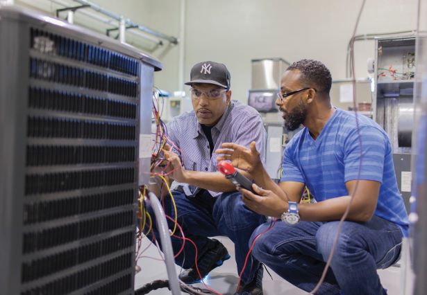 An HVAC instructor is demonstrating some components of a heat pump.