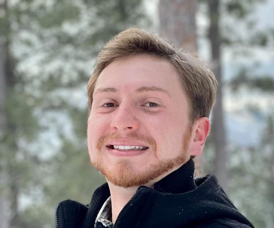 Jacob Craiger takes a selfie with a snow forest in the background.