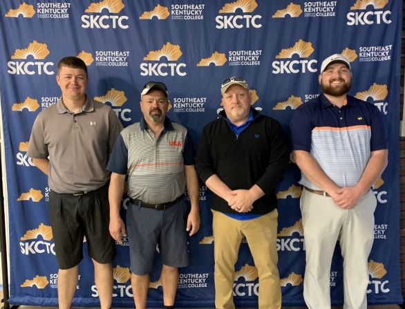 Four golfers stand in front of a college-branded backdrop.