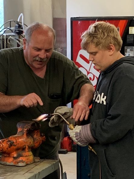 Thomas Smith shows a youth how to solder copper pipe.