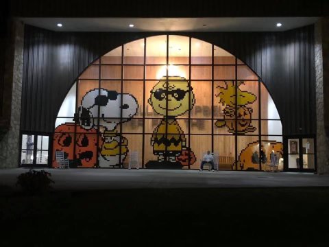 A display of Tyler Watts post-it note artwork. It is a Charlie Brown Halloween scene in the large window of a business.