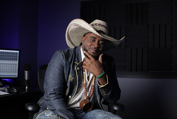 Hip-hop artist, Buffalo B Stille sitting in a music recording studio with a large cowboy hat.