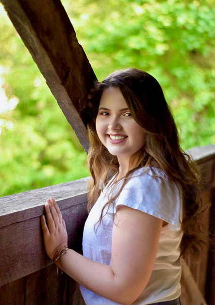 A portriat of Maridith Moore. She is posing on a wooden bridge.